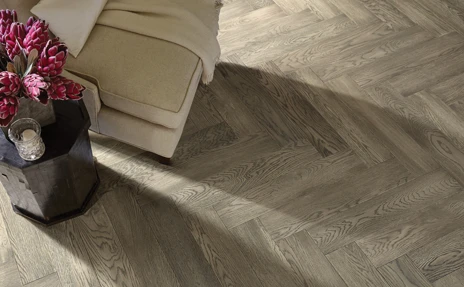 chevron pattern hardwood flooring in sitting area with cream armchair