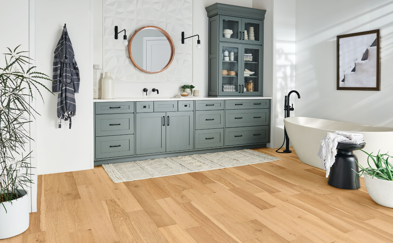 light hardwood waterproof floors in bathroom with gray cabinets and soaker tub
